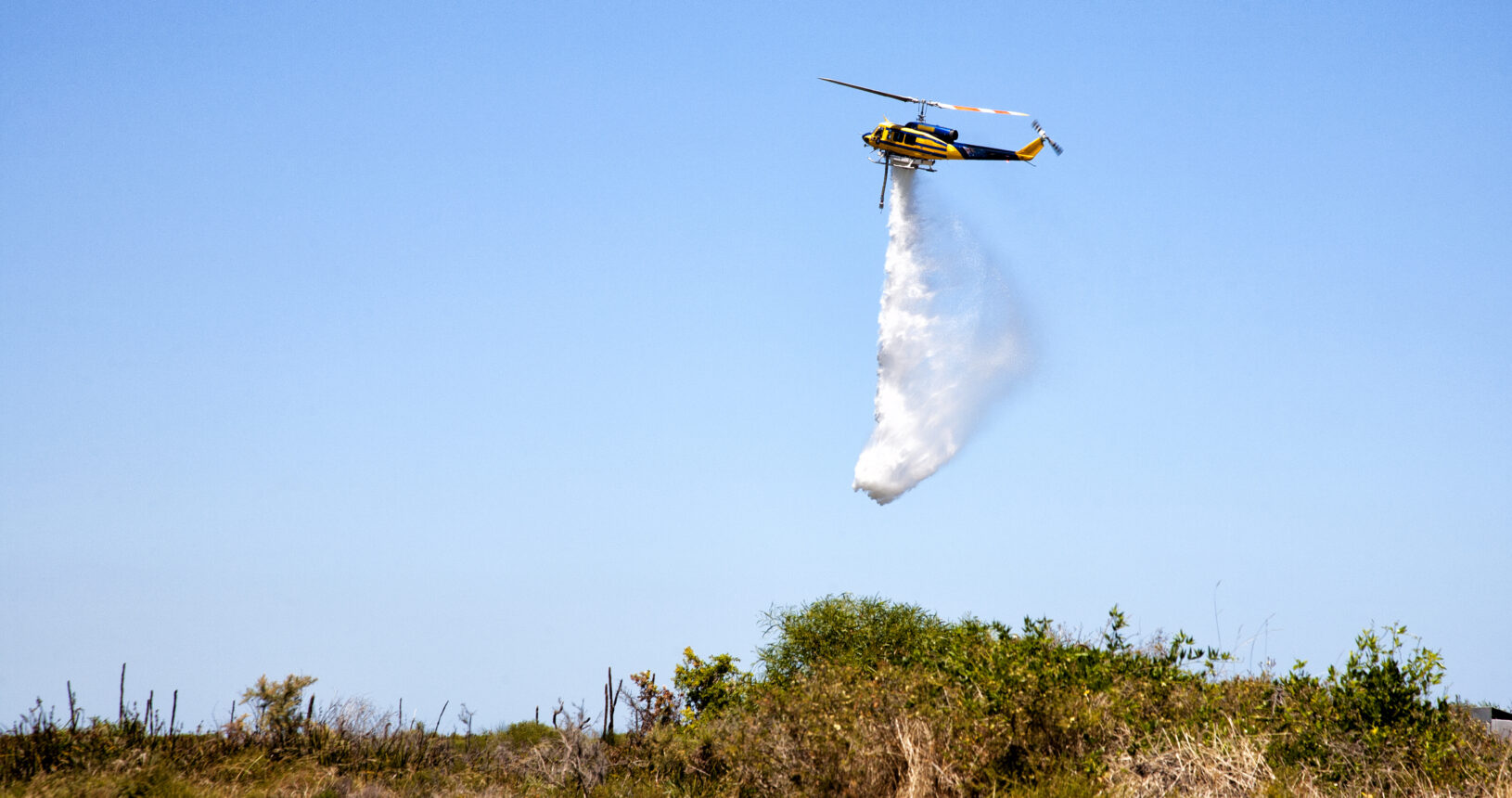 A helicopter water bomber over bush land Western australia